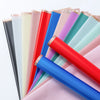 A stack of colorful floral bouquet wrapping paper rolls in various shades of pink, blue, green, and red.