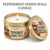 A gold tin candle labeled Peppermint Stripe Stall with a lit wick and a matching gift box.