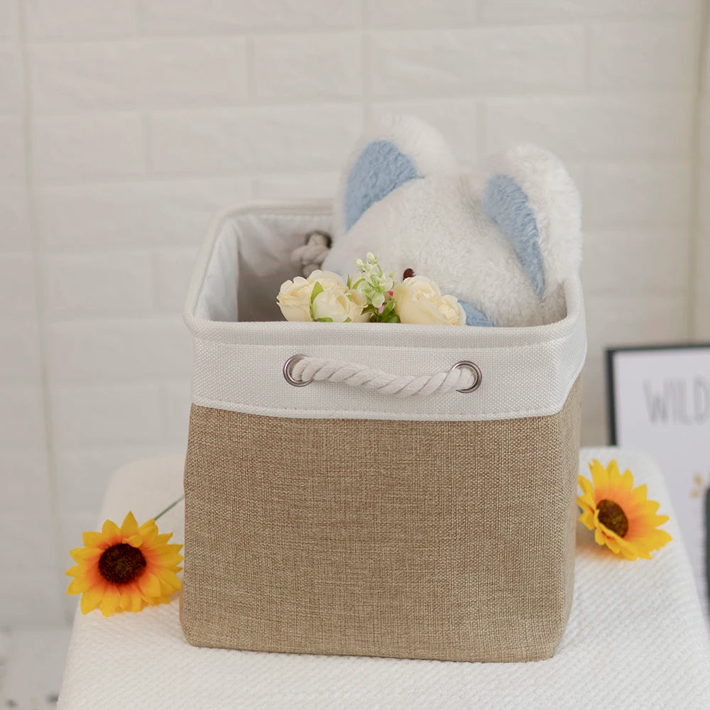 A beige fabric storage cube with a light blue stuffed animal inside, next to a yellow sunflower.