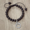 A handmade beaded bracelet with natural black stones and a silver zodiac charm
