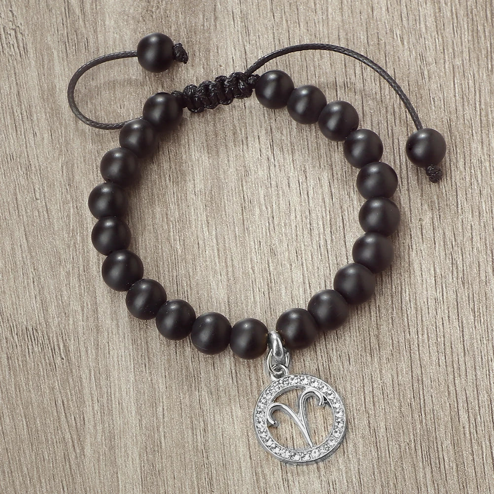 A handmade beaded bracelet with natural black stones and a silver zodiac charm