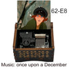 A hand-cranked wooden music box featuring a woman, with the title Music: once upon a December visible on the packaging.