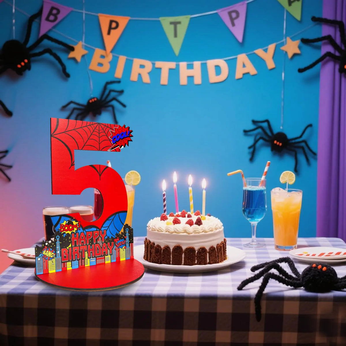 A birthday party display featuring a large red number 5, spider decorations, and a cake on a checkered tablecloth.