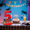 A birthday party display featuring a large red number 5, spider decorations, and a cake on a checkered tablecloth.