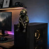 A detailed resin collectible statue of a tactical sniper soldier in green and brown armor sitting on a black computer tower.