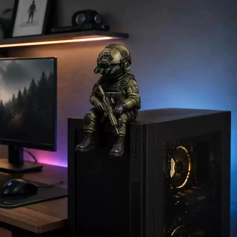 A detailed resin collectible statue of a tactical sniper soldier in green and brown armor sitting on a black computer tower.