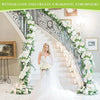 A grand staircase decorated with white floral garlands and candles, set in a bright interior.