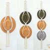 Handmade macrame hat organizer with a wooden dowel featuring beige and olive green tones.