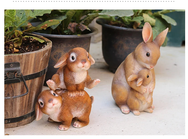 A hand-painted resin rabbit garden statue featuring a mother rabbit and her baby sitting on a light surface.