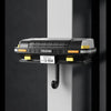 A black classic car headlight key holder with an LED illumination feature mounted on a dark wall.