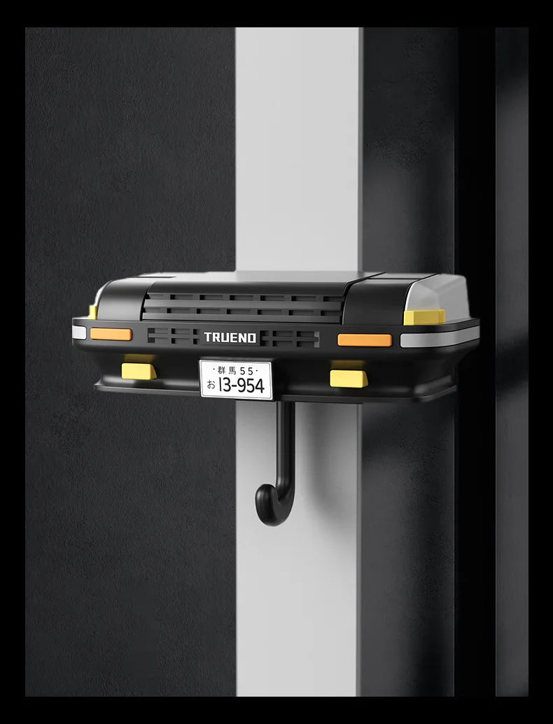 A black classic car headlight key holder with an LED illumination feature mounted on a dark wall.