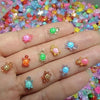 A hand displays several glow-in-the-dark resin turtle figurines in various colors on a colorful background.