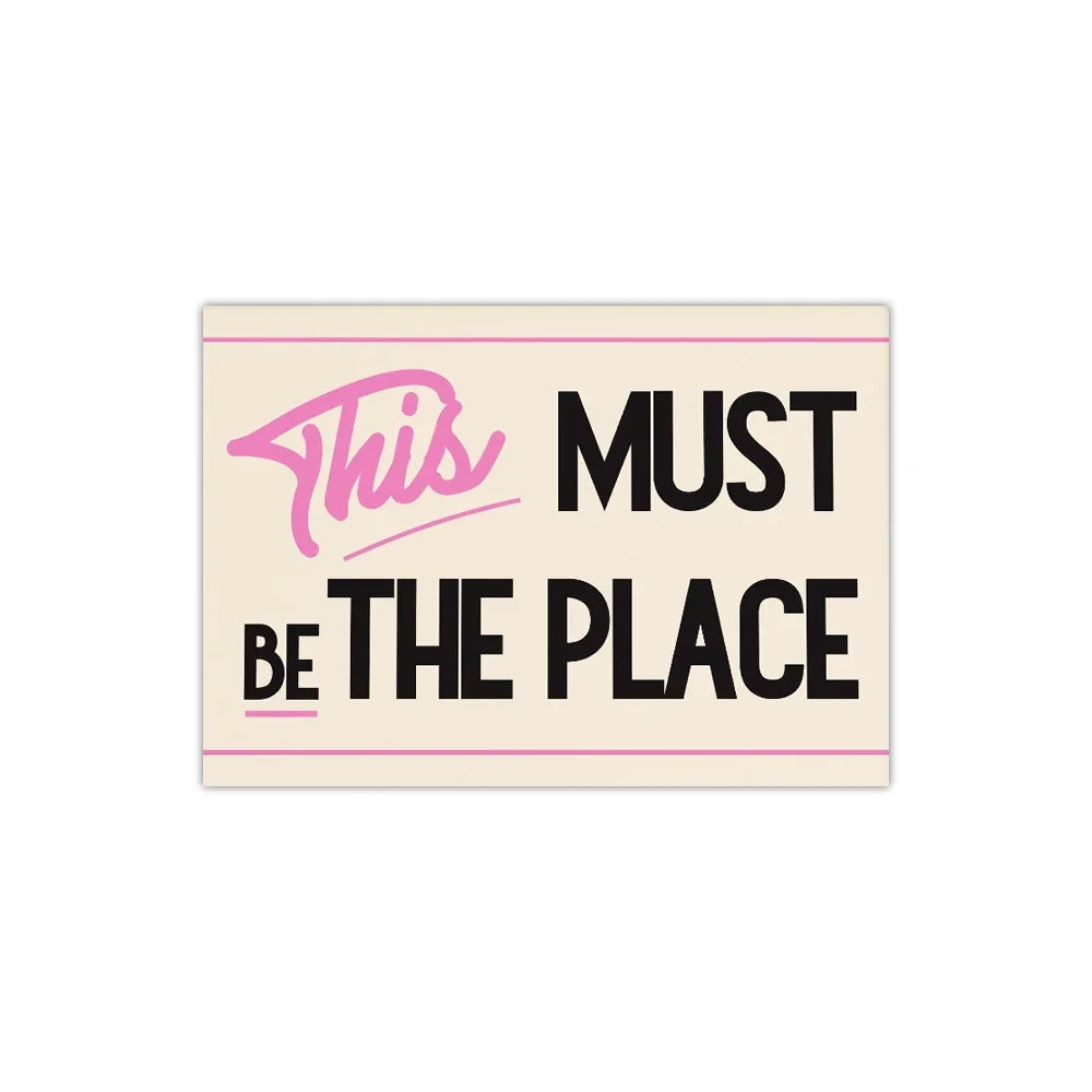 Pink and black text on a beige background reads This Must Be The Place
