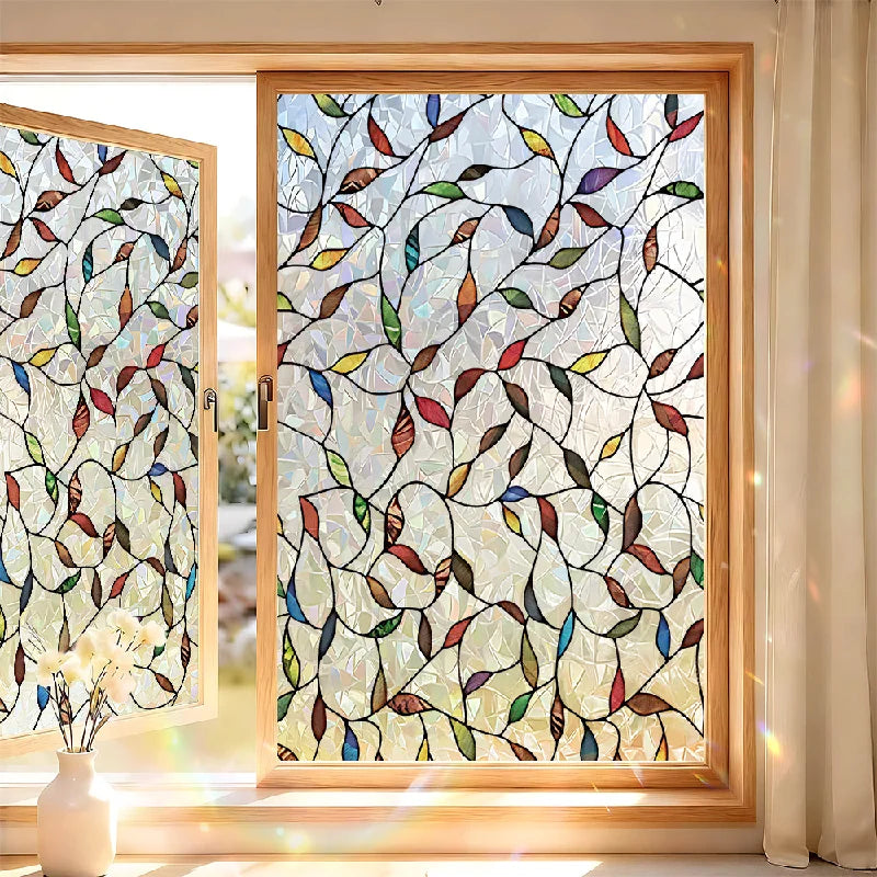 A close-up of a window featuring decorative privacy film with multicolored leaves and branches.