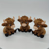 A set of three small, brown Highland cow statues with horns and black hooves displayed against a white background.