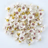 A close-up view of silk artificial flower heads with white petals and pink centers scattered on a white background.