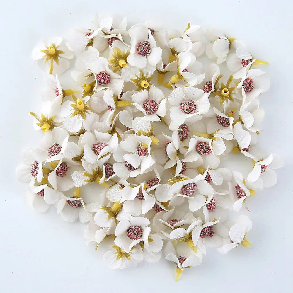 A close-up view of silk artificial flower heads with white petals and pink centers scattered on a white background.