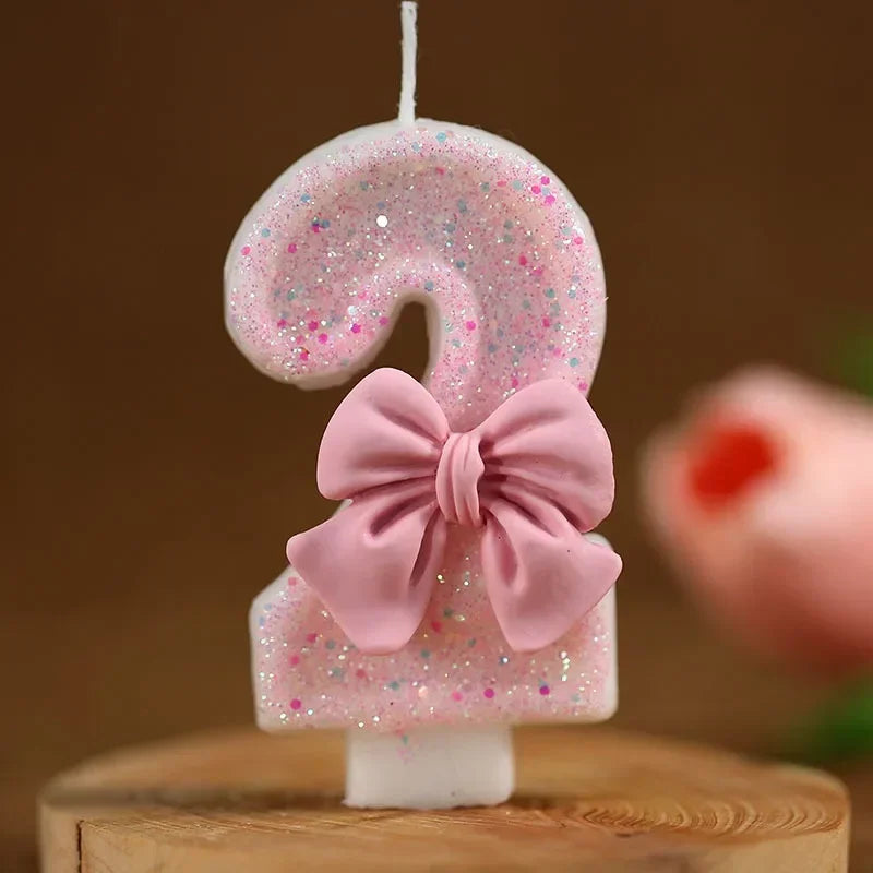 Topper de vela número 9 brillante rosa con lazo rosa sobre una superficie de madera.