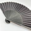 A black folding hand fan with a bamboo frame shown in profile.