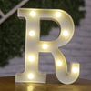 A glowing warm white LED alphabet letter light shaped like the letter R, resting on a wooden surface.