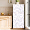 A white refrigerator with a delicate purple floral vine decal on the door, set against a light wood cabinet and window.