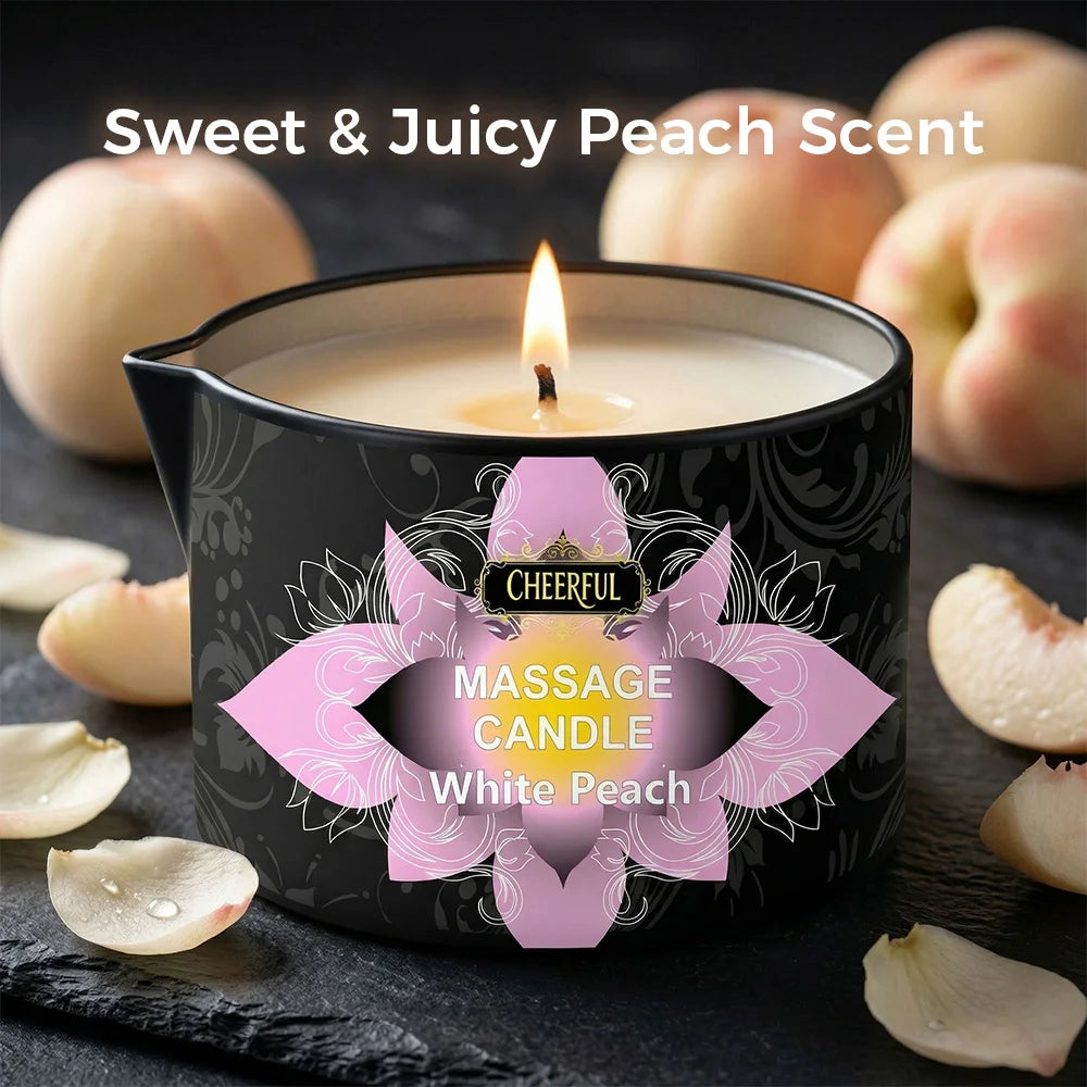 A candle in a black tin with a white peach design and a lit wick, set against a dark background.