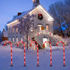 Five red and white candy cane pathway lights illuminate a snowy outdoor scene in front of a house.