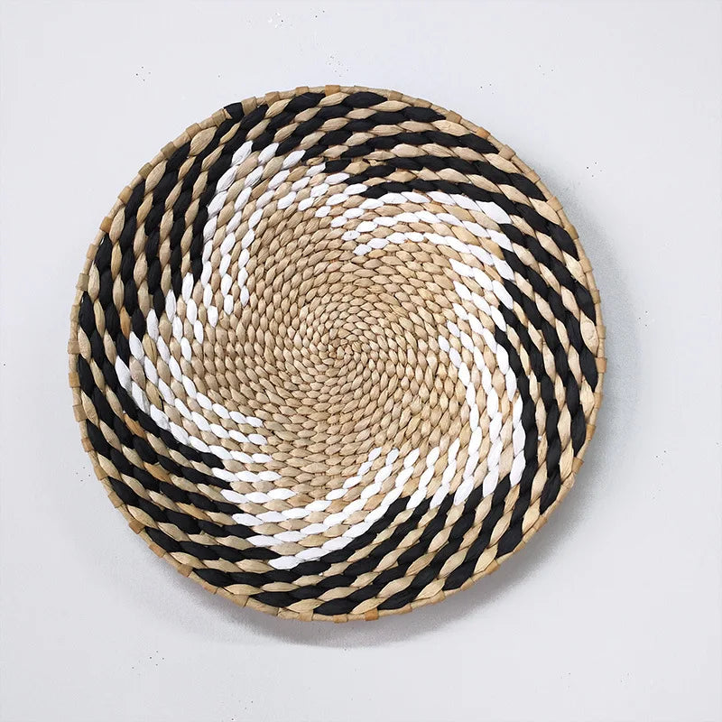 A round woven straw wall decor hanging featuring concentric black and white stripes.