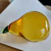A translucent yellow glass figurine shaped like a pear, used as a home decor accent.