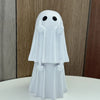 A white ghost figurine with a hood and hands raised, displayed on a white surface.