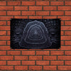A dark, intricate relief carving of a stylized face or mask is mounted on a brick wall.