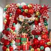 A festive balloon decoration set featuring red, gold, and green balloons arranged around a Christmas tree.