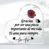A clear heart-shaped glass keepsake frame with a red rose and text that reads Gracias por ser una pieza importante de mi vida