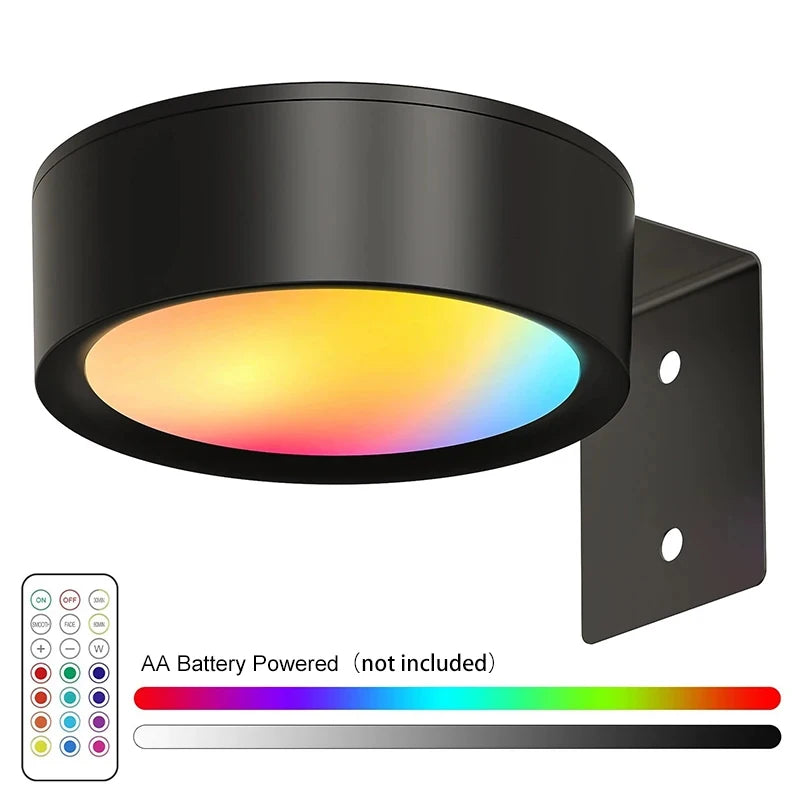 Black LED picture light with a colored lens and magnetic mount, showing an AA battery power source.