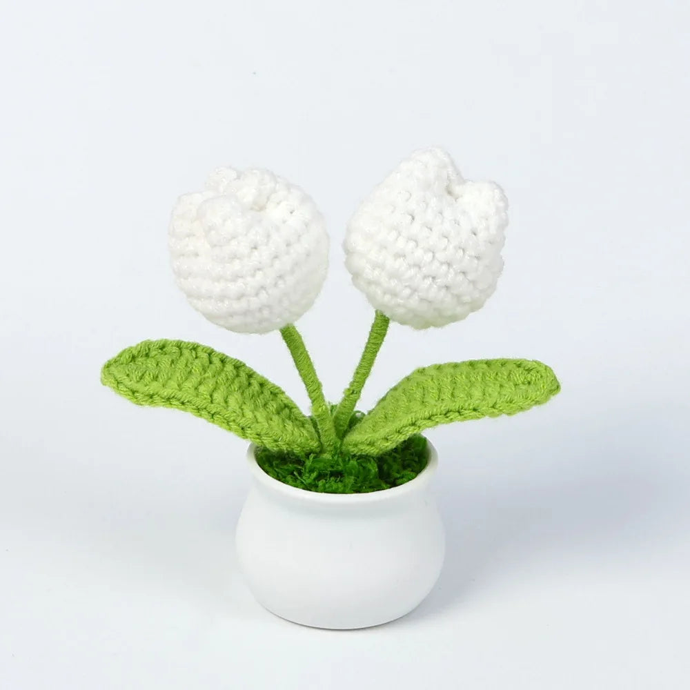 Hand woven white crochet flowers in green leaves potted in a white ceramic cup