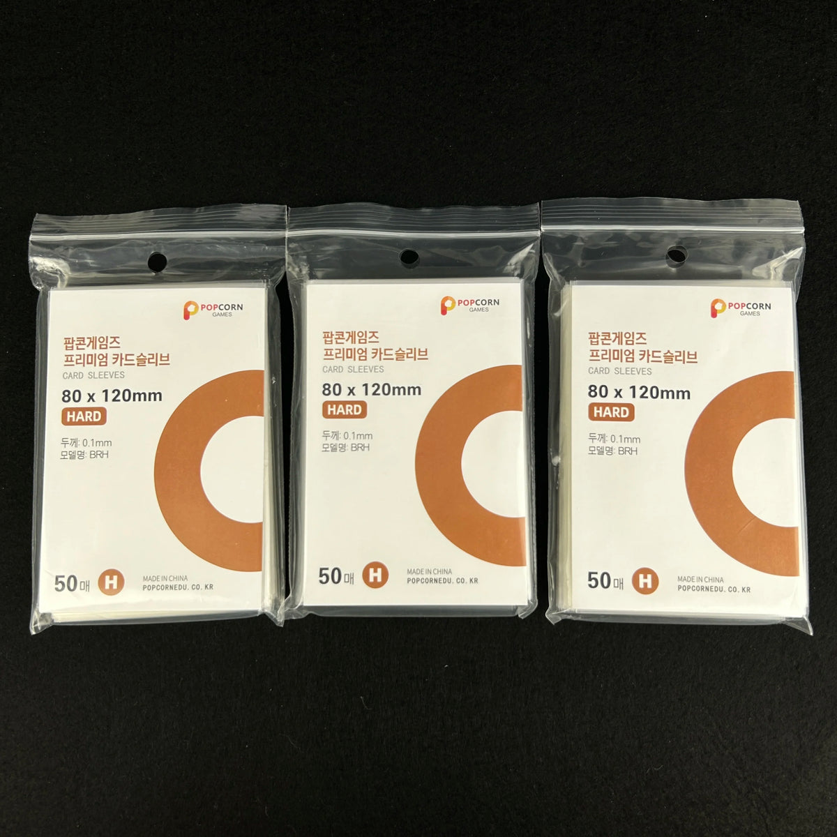 Three packs of POPCORN card sleeves with orange and white designs for protection