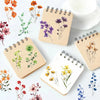 A collection of floral designs on beige and white spiral notebooks and a white cup.