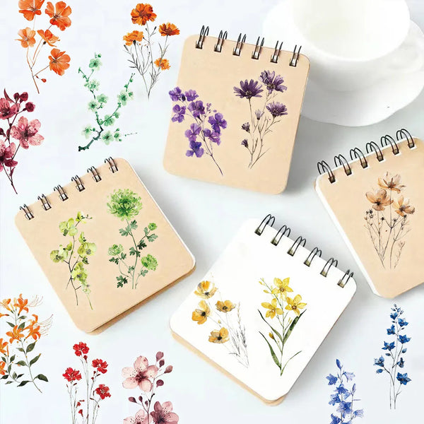 A collection of floral designs on beige and white spiral notebooks and a white cup.