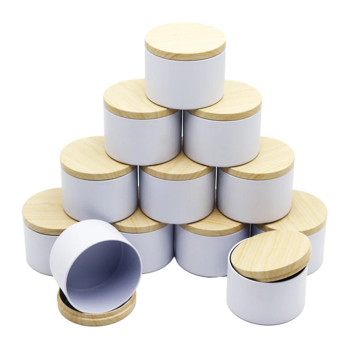 A stack of metal candle tins with wooden lids in white and natural wood tones.