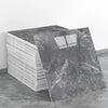 A stack of rectangular gray marble effect self-adhesive wall stickers on a gray floor.