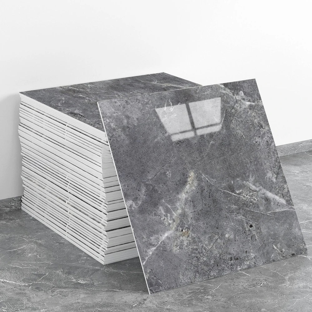 A stack of rectangular gray marble effect self-adhesive wall stickers on a gray floor.