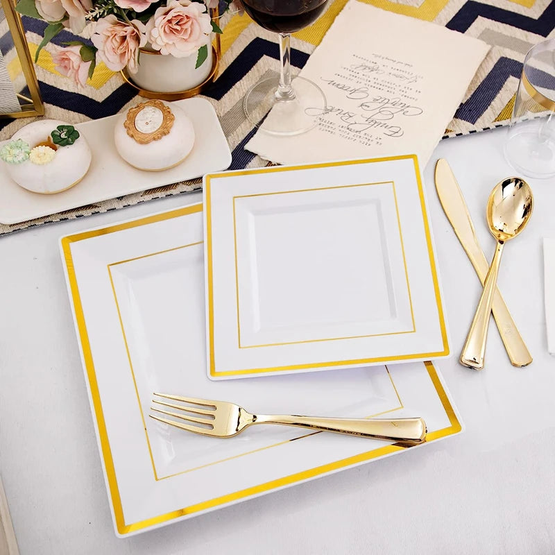 A set of gold plastic dinnerware plates and cutlery is displayed on a white tablecloth with floral accents.