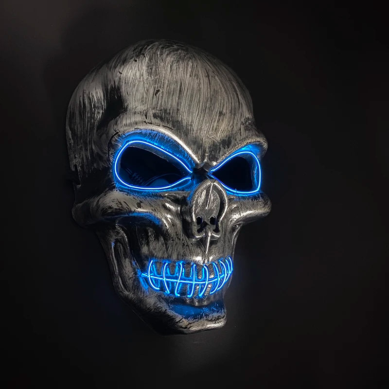 A realistic latex skull mask with glowing blue eyes and teeth against a dark background.