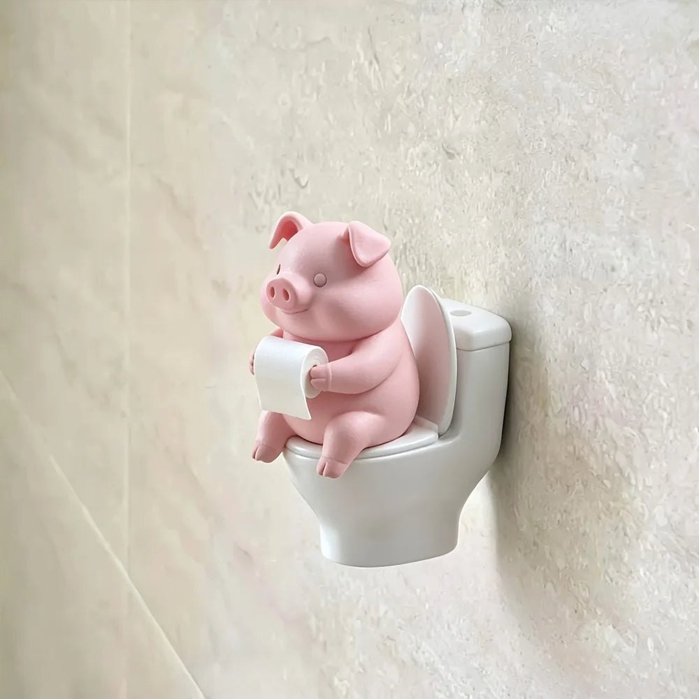 Figurine de cochon en céramique rose assise sur un siège de toilette blanc.
