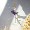 A gold dreamcatcher hangs, featuring a purple crescent moon and clear crystal beads, catching sunlight.