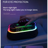 A hand is interacting with a black speaker lamp that emits warm night light and features a digital display.