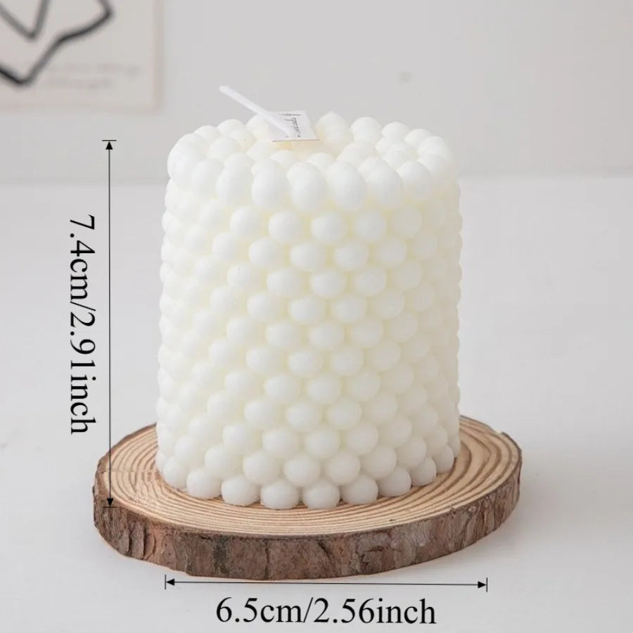 A white Nordic bubble scented soy candle is displayed on a wooden slice.