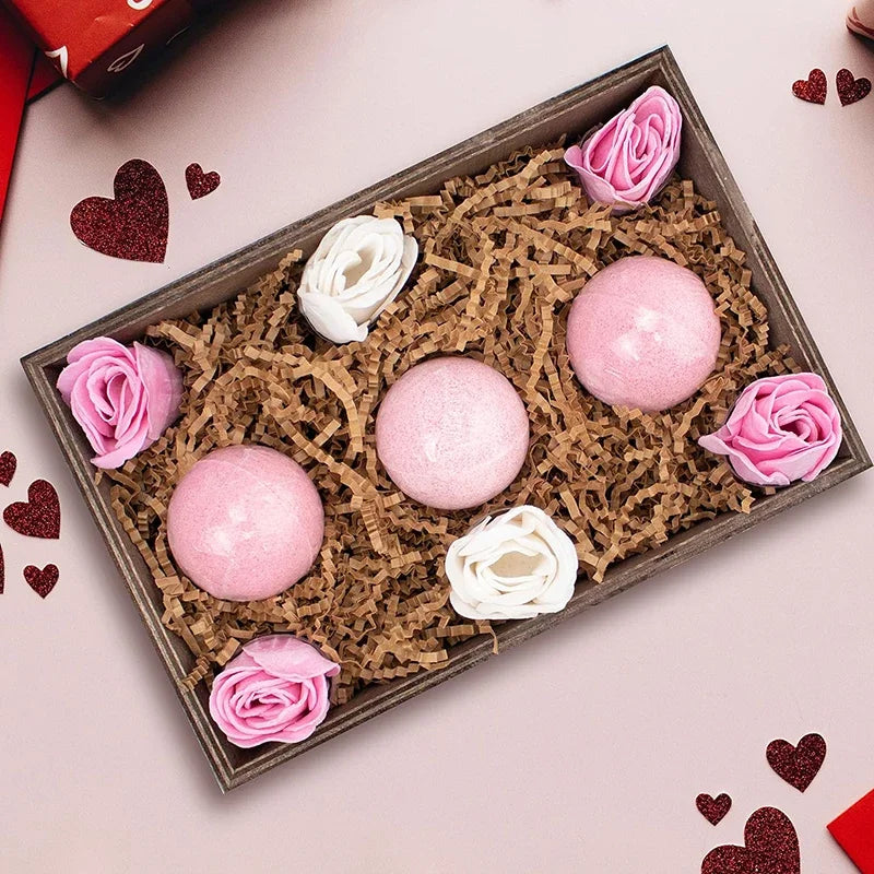 Holzkiste mit rosa und weißen Blumendekorationen, Rosen und Glitzerbällen, auf braunem zerfetztem Papier