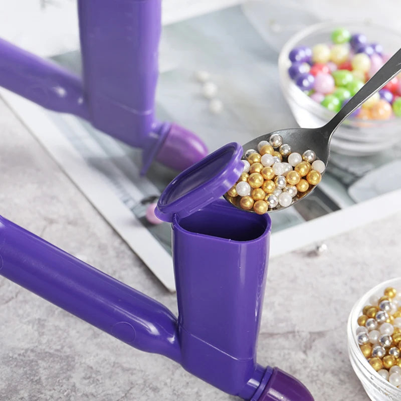 A purple DIY pearl ball applicator tool is shown with a spoon filled with gold and pearl balls for cake decorating.