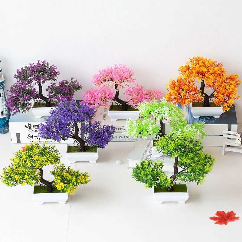A collection of artificial tree bonsai decorations in various shades of purple, pink, and orange displayed on a white surface
